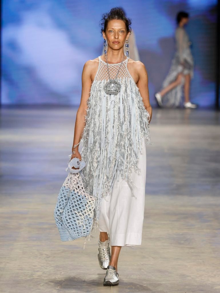 Modelo desfila com sombrinha branca de trama vazada e roupa clara da Catarina Mina na SPFW N61.