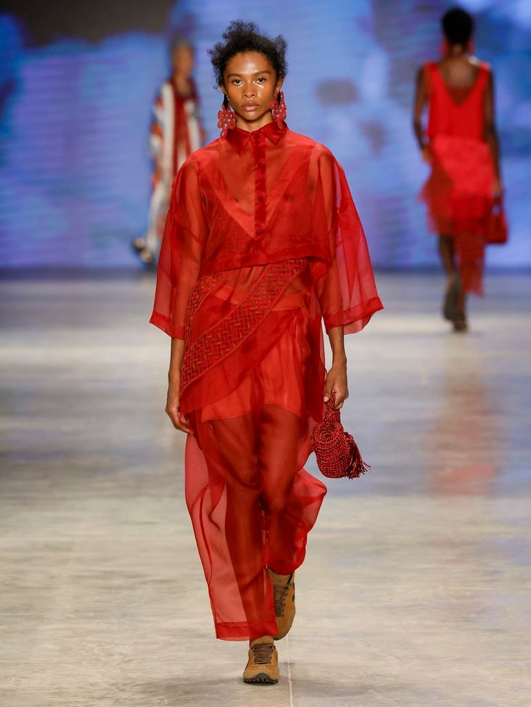 Modelo de cabelos brancos apresenta vestido de faixas multicoloridas e trama azul no desfile Catarina Mina da SPFW N61.