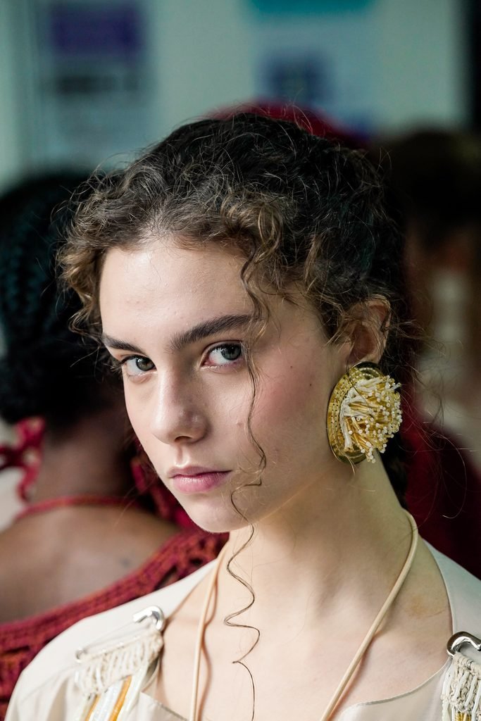 Modelos nos bastidores do desfile Catarina Mina com roupas claras e acessórios artesanais na SPFW N61.